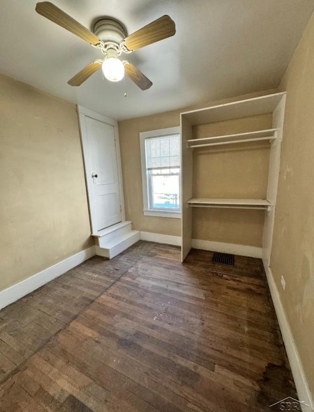 unfurnished bedroom featuring dark wood-style floors, ceiling fan, baseboards, and a closet