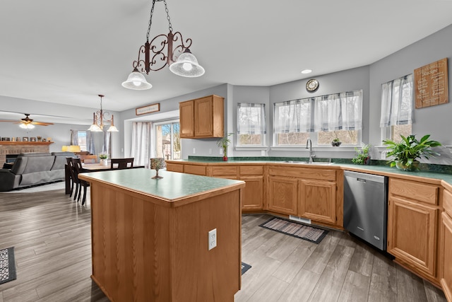 kitchen featuring light wood finished floors, a center island, pendant lighting, dishwasher, and a sink