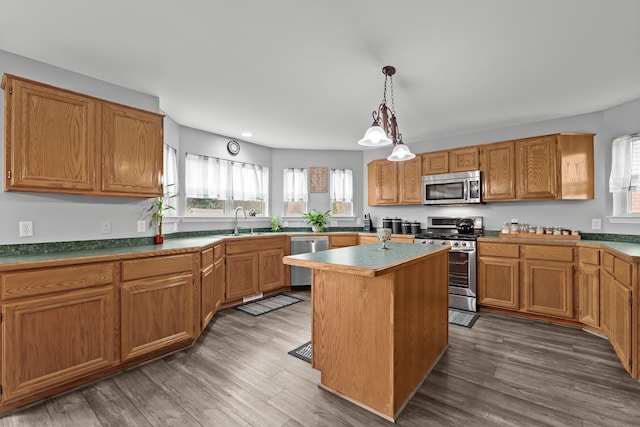 kitchen with a center island, stainless steel appliances, dark wood-type flooring, and a sink