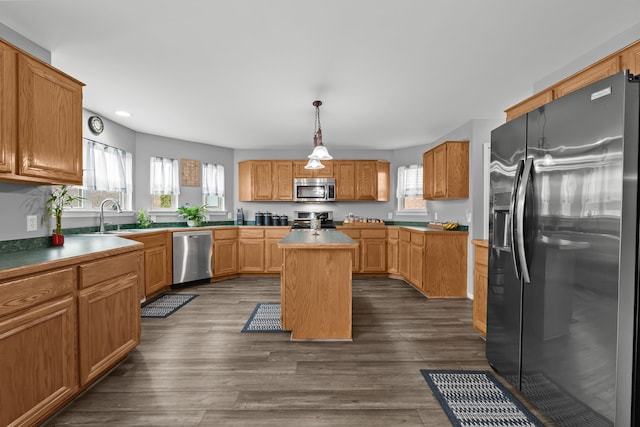 kitchen with a sink, appliances with stainless steel finishes, dark wood finished floors, and a center island