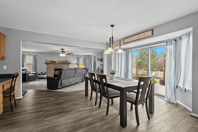 dining space featuring a brick fireplace, wood finished floors, and baseboards