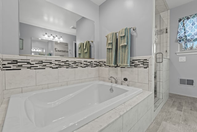 full bathroom featuring visible vents, a garden tub, and a stall shower