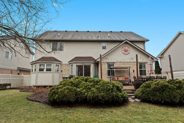 back of house featuring a yard, fence, and brick siding