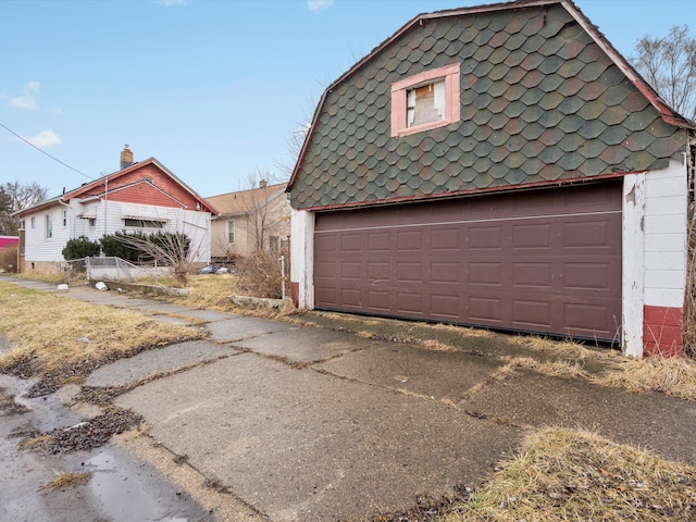 view of property exterior with a garage, an outbuilding, and driveway