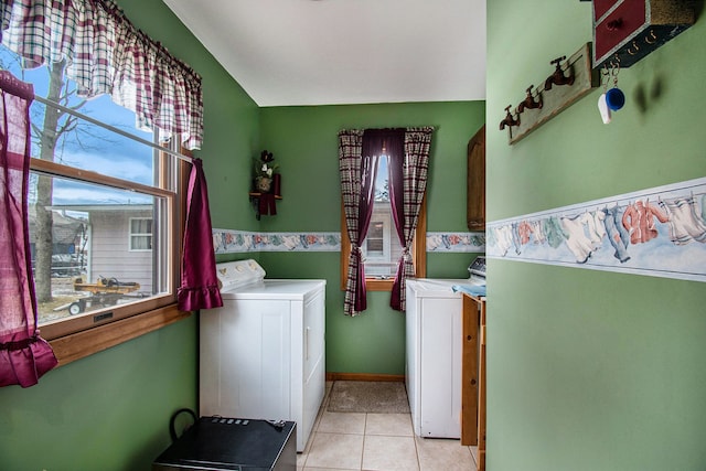 washroom featuring laundry area, washer and clothes dryer, light tile patterned flooring, and baseboards