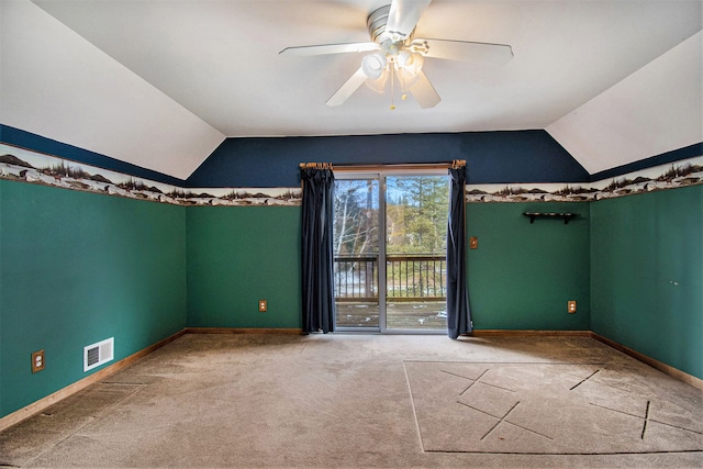 carpeted empty room featuring lofted ceiling, visible vents, ceiling fan, and baseboards