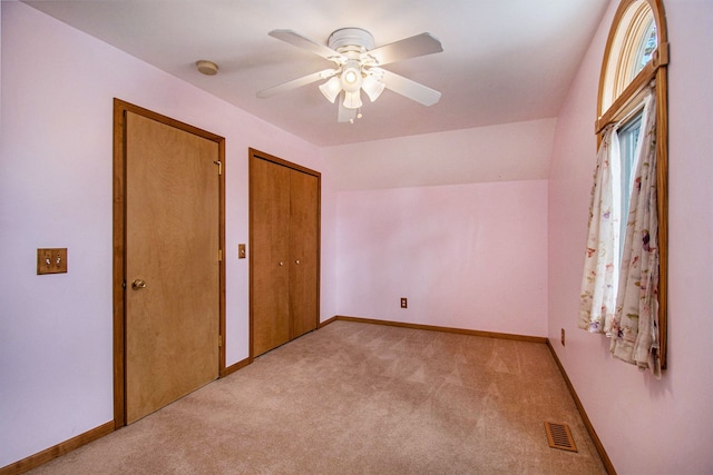 unfurnished bedroom with visible vents, light carpet, baseboards, and two closets