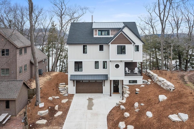 view of front of house featuring a garage, metal roof, driveway, and a shingled roof