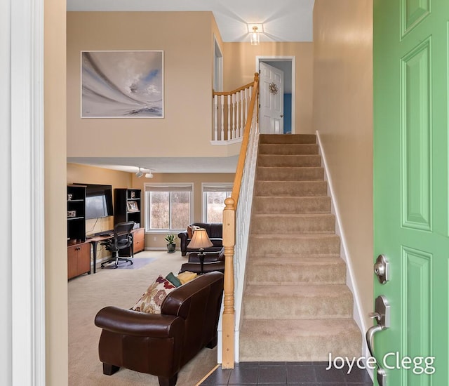 stairway with a high ceiling, carpet flooring, and baseboards