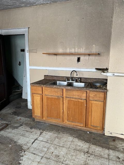 kitchen featuring brown cabinetry, dark countertops, and a sink