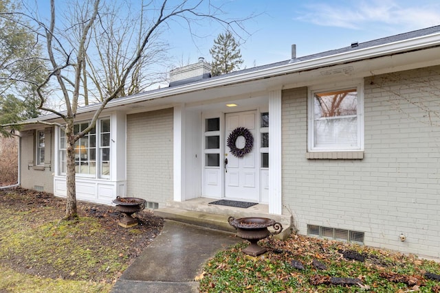 doorway to property with crawl space, a chimney, visible vents, and brick siding