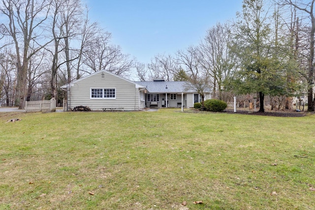 rear view of house featuring a yard and fence