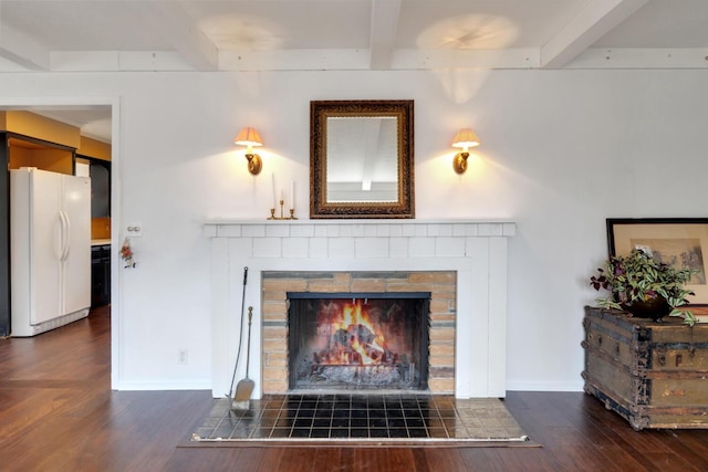 details featuring baseboards, a tile fireplace, wood finished floors, freestanding refrigerator, and beam ceiling