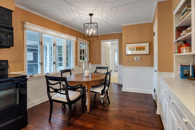 dining area with wallpapered walls, wainscoting, dark wood-style floors, ornamental molding, and an inviting chandelier