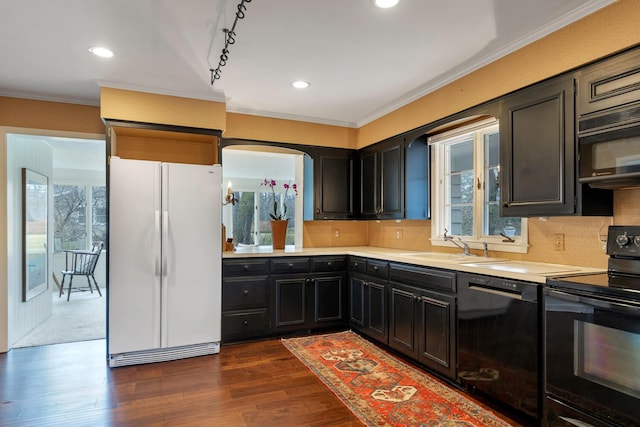 kitchen featuring a wealth of natural light, light countertops, dark wood-type flooring, a sink, and black appliances