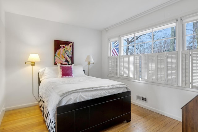 bedroom with light wood-style flooring, visible vents, and baseboards