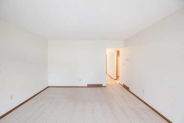 unfurnished room with light colored carpet and baseboards