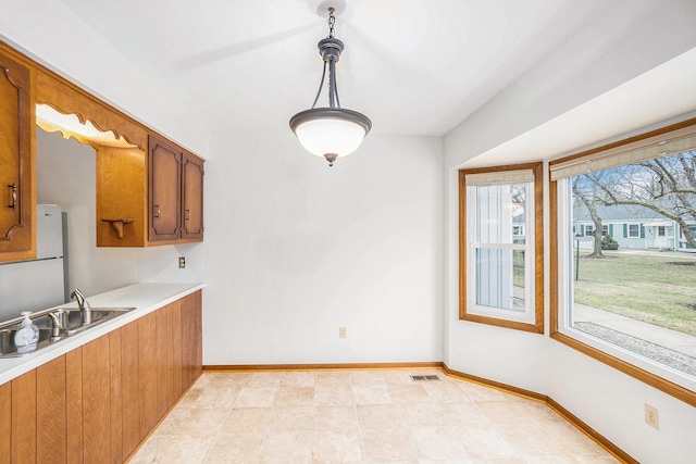 kitchen with light countertops, brown cabinets, visible vents, and baseboards