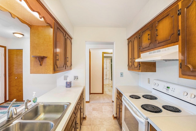 kitchen featuring under cabinet range hood, white electric range, a sink, light countertops, and brown cabinetry