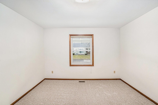 carpeted spare room with visible vents and baseboards