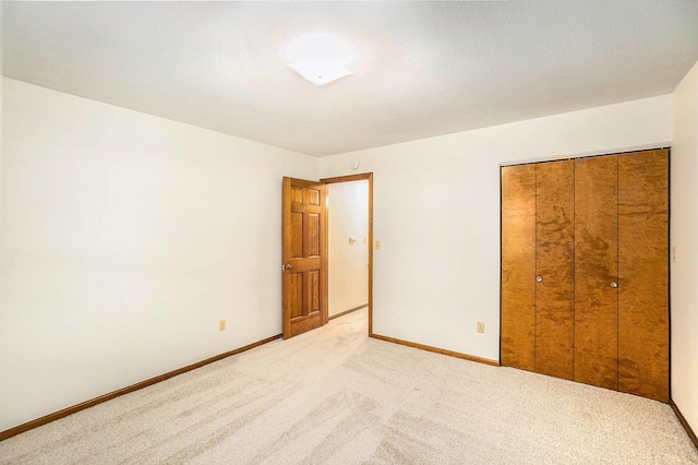 unfurnished bedroom with baseboards, a closet, and light colored carpet