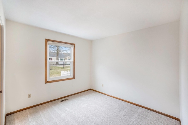 empty room with carpet floors, baseboards, and visible vents