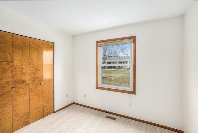 unfurnished bedroom featuring a closet, visible vents, light carpet, and baseboards