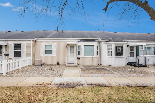 multi unit property featuring a shingled roof and fence