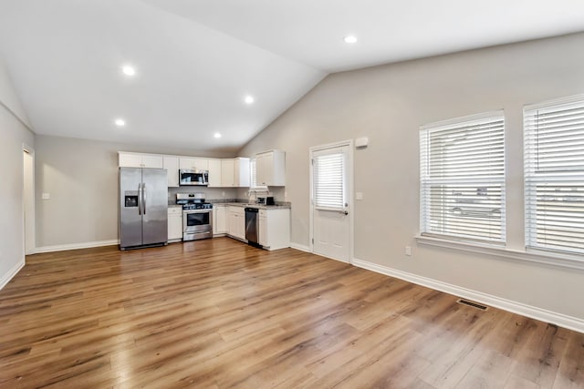 kitchen with vaulted ceiling, appliances with stainless steel finishes, light wood finished floors, and visible vents