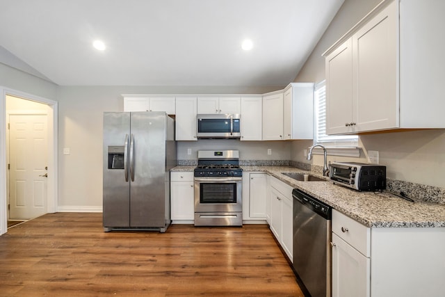 kitchen featuring a toaster, stainless steel appliances, white cabinetry, a sink, and wood finished floors