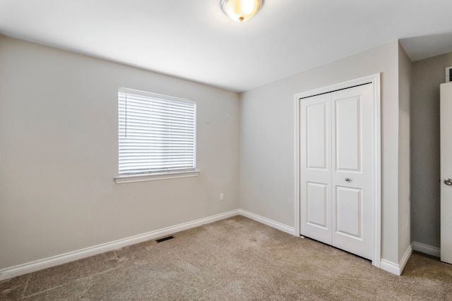 unfurnished bedroom with carpet floors, a closet, visible vents, and baseboards