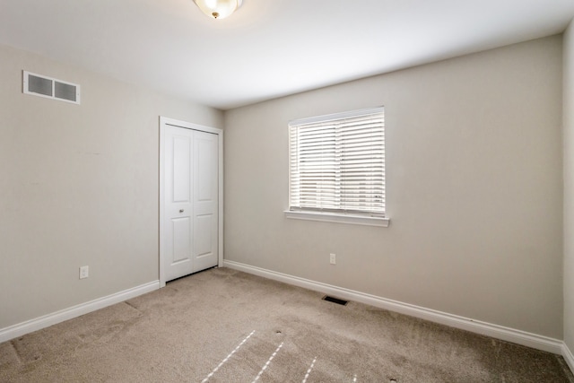 unfurnished bedroom with carpet floors, visible vents, and baseboards