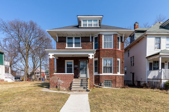 traditional style home with a front yard, covered porch, and brick siding