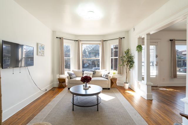 living area with decorative columns, baseboards, and wood finished floors