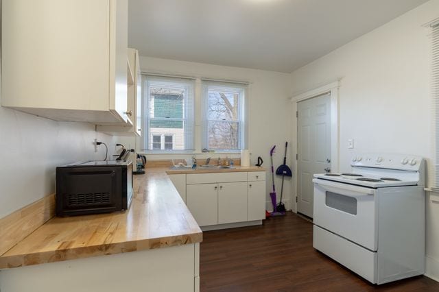 kitchen featuring dark wood-style floors, white cabinetry, a sink, and electric range