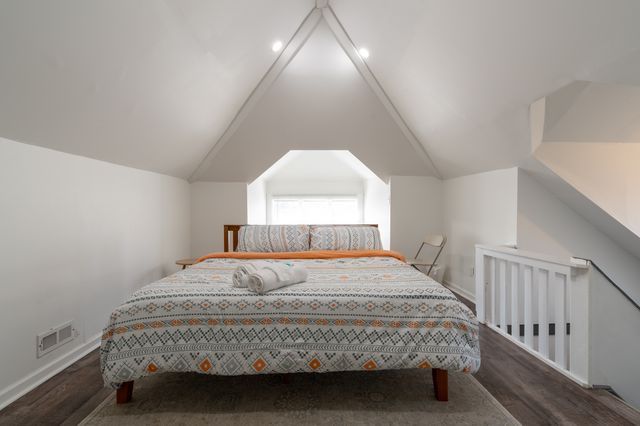 bedroom with lofted ceiling, visible vents, baseboards, and wood finished floors