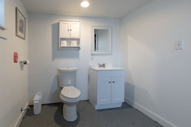 bathroom featuring speckled floor, vanity, toilet, and baseboards