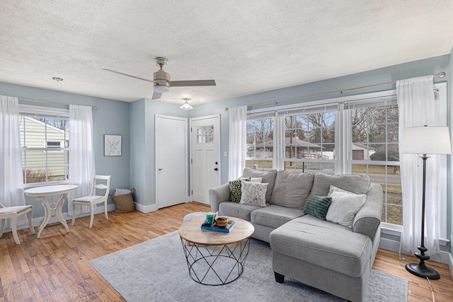 living room with baseboards, ceiling fan, a textured ceiling, and hardwood / wood-style floors