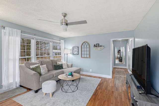 living room featuring ceiling fan, wood finished floors, attic access, and baseboards