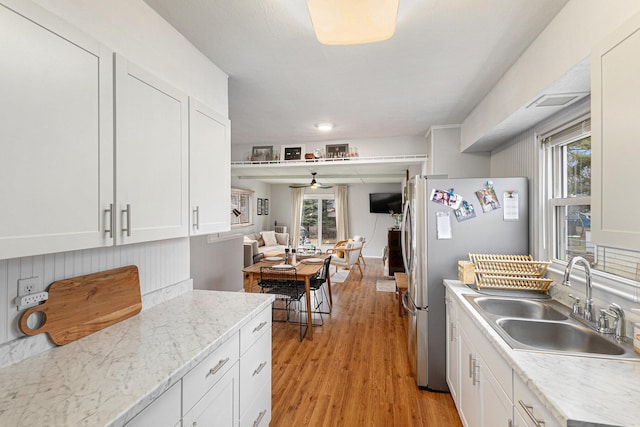 kitchen with light wood-type flooring, freestanding refrigerator, a wealth of natural light, and a sink