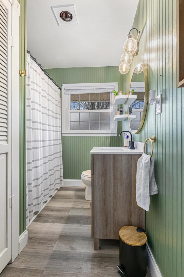 full bathroom featuring curtained shower, toilet, vanity, wood finished floors, and baseboards