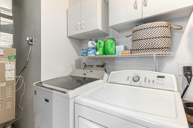 laundry area featuring washing machine and clothes dryer and cabinet space