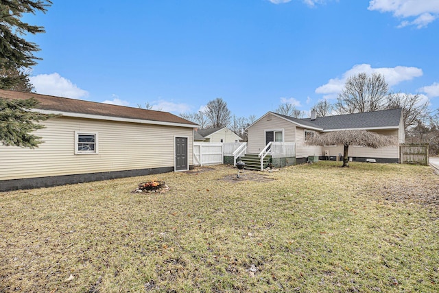 rear view of house with crawl space, an outdoor fire pit, fence, and a lawn