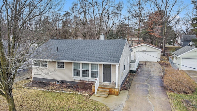 view of front of home with a garage, roof with shingles, an outbuilding, and a chimney