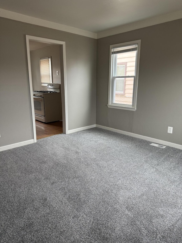 unfurnished room with dark carpet, visible vents, and baseboards