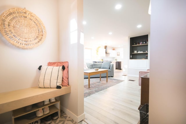 corridor with light wood-type flooring, baseboards, and recessed lighting