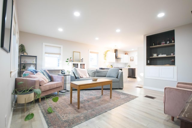 living room featuring light wood-style floors, baseboards, visible vents, and recessed lighting