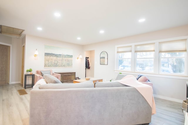 living area with light wood-type flooring, attic access, baseboards, and recessed lighting