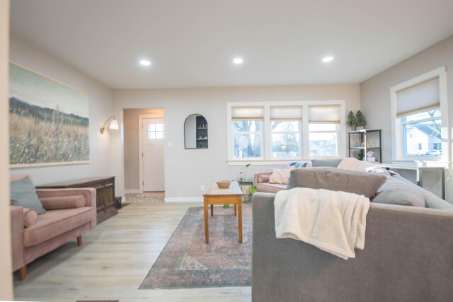 living area featuring baseboards, light wood finished floors, and recessed lighting