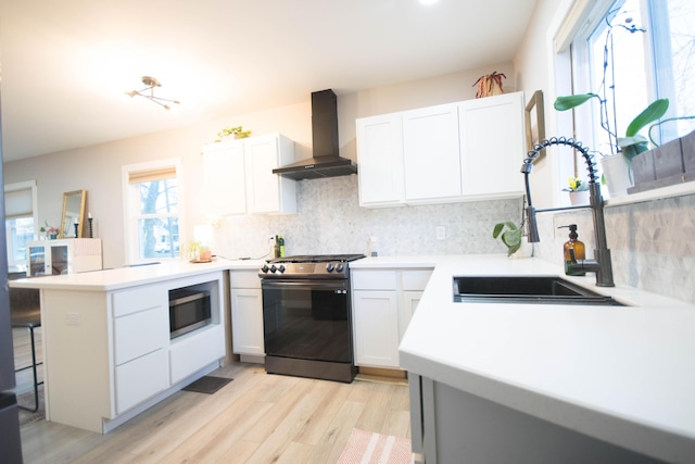 kitchen with tasteful backsplash, a peninsula, stainless steel appliances, wall chimney range hood, and a sink